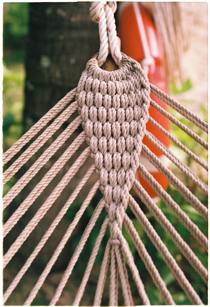 Close-up view of a woven rope hammock hanging outdoors with intricate patterns.