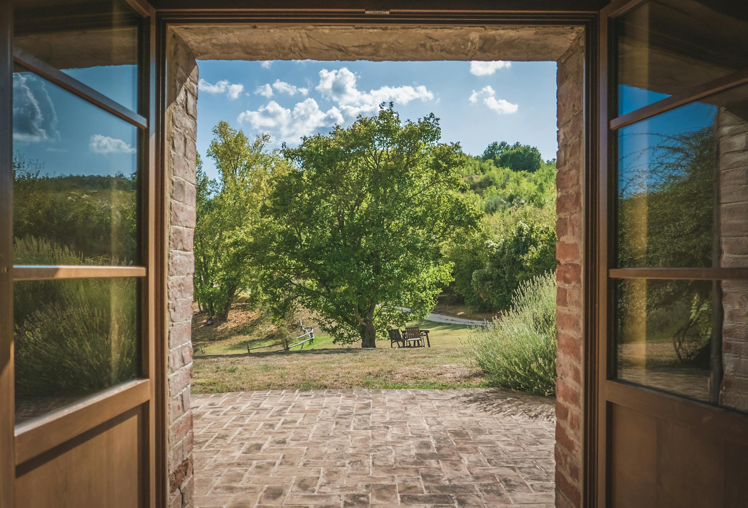 Admire the lush Italian landscape through a classic stone doorway in Umbria.