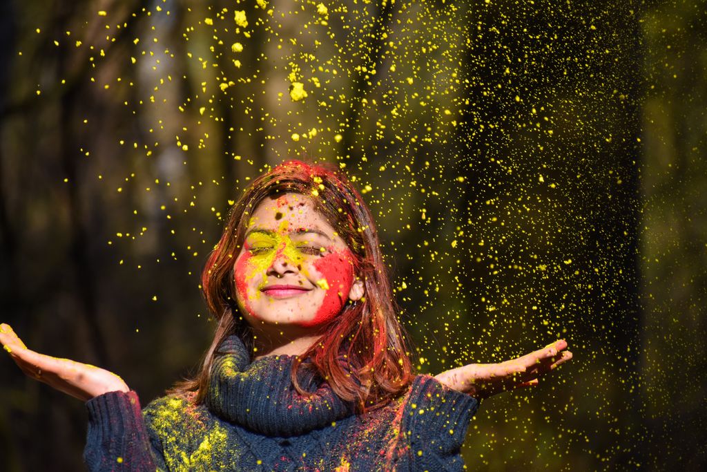 Vibrant portrait of a woman enjoying Holi with colorful powder on her face.